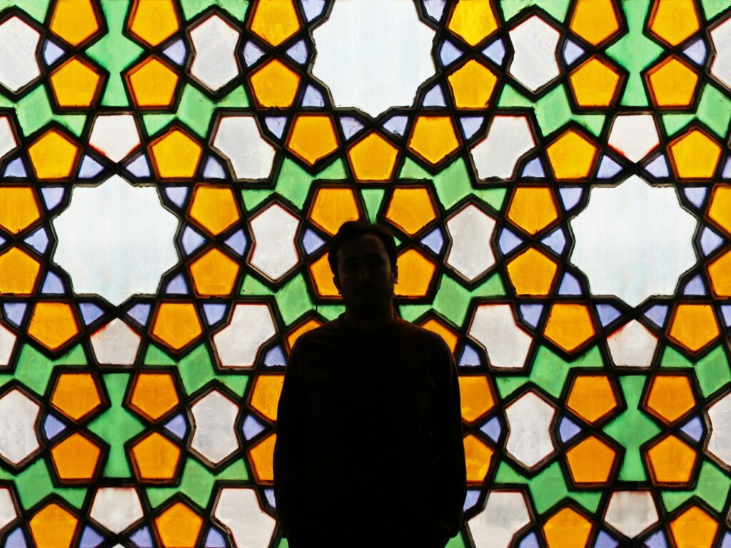 A man standing in front of a Persian window.