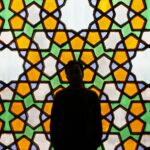 A man standing in front of a Persian window.