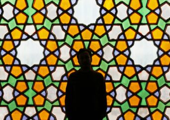 A man standing in front of a Persian window.